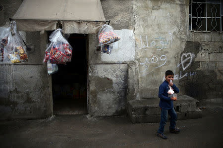 A boy carries goods outside a grocery shop in the rebel held besieged city of Douma, in the eastern Damascus suburb of Ghouta, Syria February 12, 2017. REUTERS/Bassam Khabieh