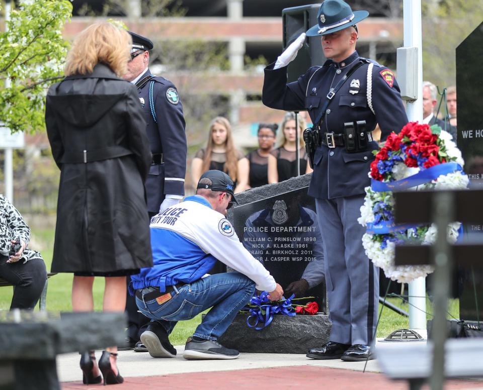 FILE - Kevin Casper lays a rose at a fallen police officer monument at the annual Fond du Lac Police Department memorial ceremony May 13, 2021, in Hamilton Park in Fond du Lac. The ceremony honors and pays tribute to all of the nation's fallen law enforcement officers and, in particular, those who have made the ultimate sacrifice on Fond du Lac City streets: City of Fond du Lac police officers William Prinslow, Nick Klaske and Craig Birkholz, and Wisconsin State Patrol Trooper Trevor Casper, who is Kevin's son.