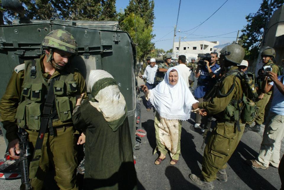 This undated publicity photo released by Kino Lorber, Inc. shows co-director Emad Burnat's mother, pleading with an Israeli soldier to release her son Khaled after he was arrested, in a scene from the documentary film, "5 Broken Cameras," by Burnat and co-director, Guy Davidi. (AP Photo/Kino Lorber, Inc.)