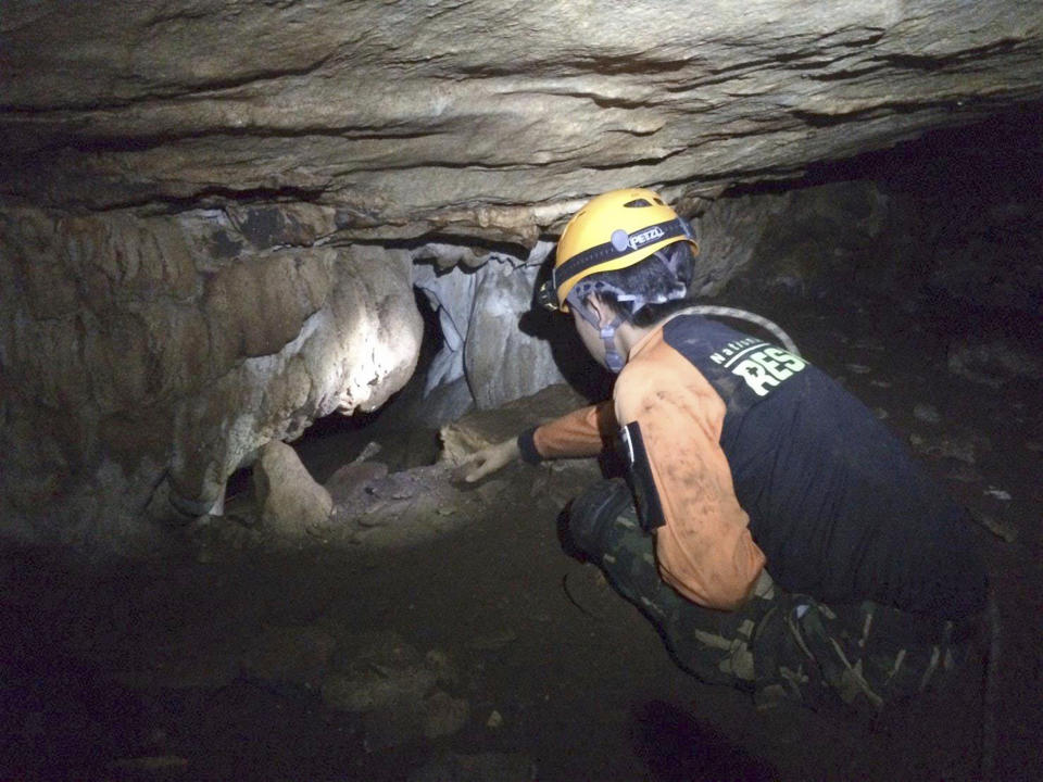 Rescue personnel search for alternate entrances to a cave. Source: AP