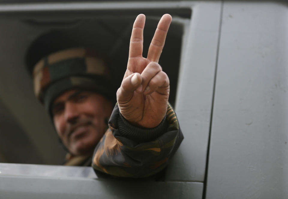 An Indian soldier flashes a victory sign as he leaves the site of a gun-battle in Mujagund area some 25 Kilometers (16 miles) from Srinagar, Indian controlled Kashmir, Sunday, Dec. 9, 2018. Indian troops killed three suspected rebels in the outskirts of disputed Kashmir's main city ending nearly 18-hour-long gunbattle, officials said Sunday. (AP Photo/Mukhtar Khan)