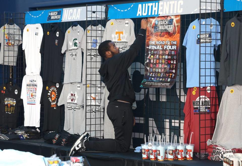 Kamoni McHarris with Hornets Entertainment finishes hanging merchandise in a souvenir stand for the 2024 NCAA Men’s Basketball First/Second Rounds at Spectrum Center in Charlotte, NC on Wednesday, March 20, 2024. Games for the tournament begin on Thursday, March 21, 2024 and conclude on Saturday, March 23, 2024. JEFF SINER/jsiner@charlotteobserver.com