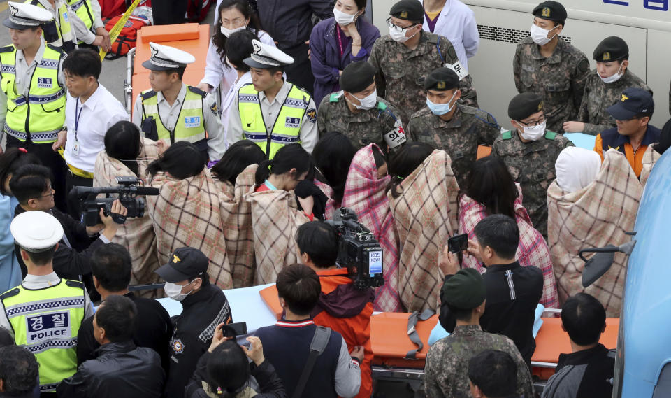 Rescued passengers from a ferry sinking off South Korea's southern coast, are escorted by rescue teams on their arrival at a port in Jindo, south of Seoul, South Korea, Wednesday, April 16, 2014. More than 100 people were still unaccounted Wednesday several hours after the ferry carrying 476, most of them high school students, sank in cold waters off South Korea's southern coast. (AP Photo/Yonhap, Park Chul-heung) KOREA OUT