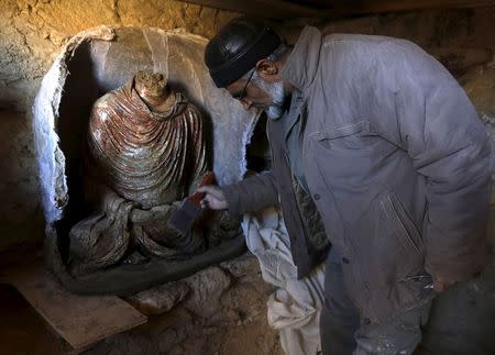 An Afghan archeologist cleans a headless Buddha statue discovered inside an ancient temple in Mes Aynak, Logar province February 14, 2015. REUTERS/Omar Sobhani