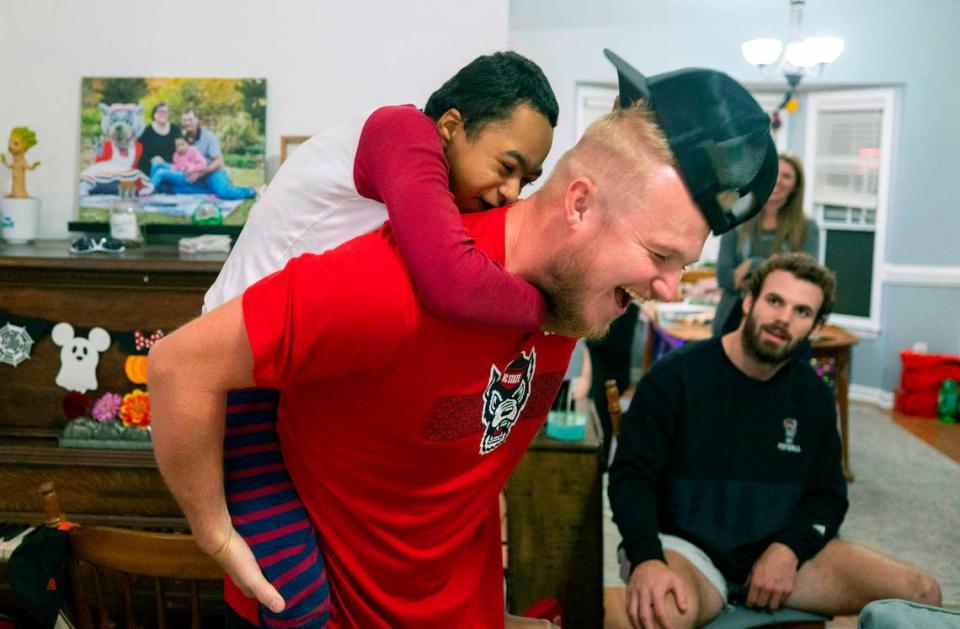 Grayson Ketchie playfully pulls the hat from N.C. State kicker Brayden Narveson as Narveson and other Wolfpack players visit Grayson’s home in Garner Wednesday, Oct. 18, 2023. Ketchie, 12, has been suffering from severe neurological issues since he was a baby. He has been a Wolfpack fan since he was three and the players made a surprise visit to his home that evening.