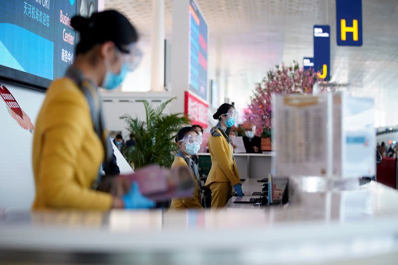 Staff members wearing face masks and goggles are seen at a counter at the Wuhan Tianhe International Airport