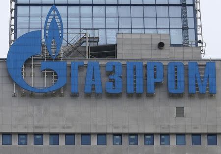 An employee stands near a window, with the company logo of installed on a building, at the headquarters of the Russian natural gas producer Gazprom in Moscow, February 24, 2015. REUTERS/Maxim Zmeyev