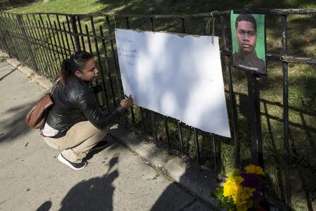 A woman signs a makeshift memorial near the scene where the shooting of officer Randolph Holder occurred in the Manhattan borough of New York, October 21, 2015. REUTERS/Andrew Kelly