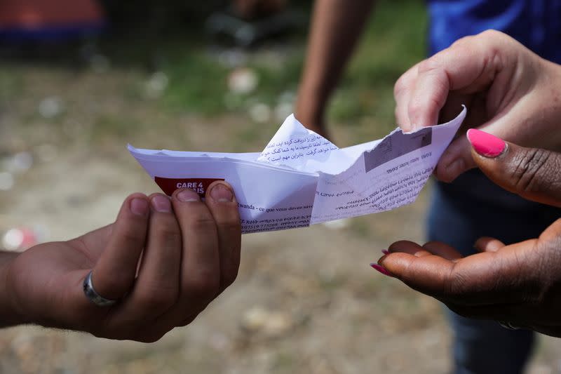 Mohamed, a young Kurdish migrant, gives to charity workers an origami boat that he built in a makeshift camp in Grande-Synthe