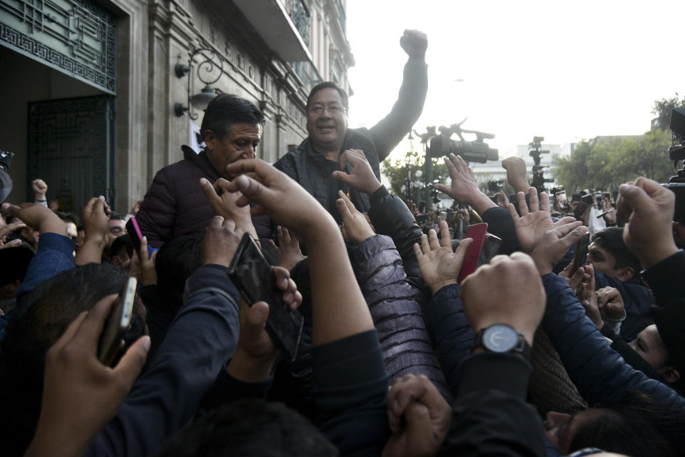 Bolivian President Luis Arce raises a clenched fist surrounded by supporters and media, outside the government palace in La Paz, Bolivia, Wednesday, June 26, 2024. Armored vehicles rammed the doors of Bolivia's government palace Wednesday in an apparent coup attempt against Arce, but he vowed to stand firm and named a new army commander who ordered troops to stand down. (AP Photo/Rodwy Cazon Barrios)