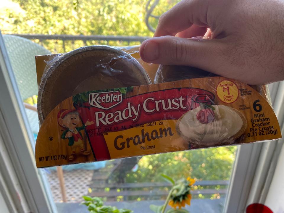 Graham cracker crust tins held in front of a window