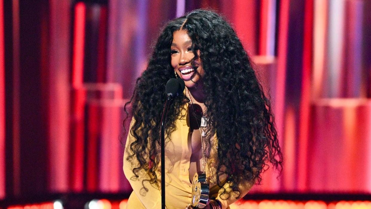 SZA in a yellow dress in front of a red background