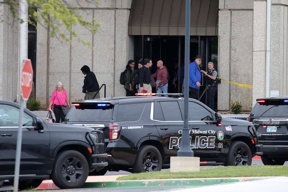 People leave a building Monday as law enforcement stand outside near the scene of a shooting that left one dead on the campus of Rose State College in Midwest City.
