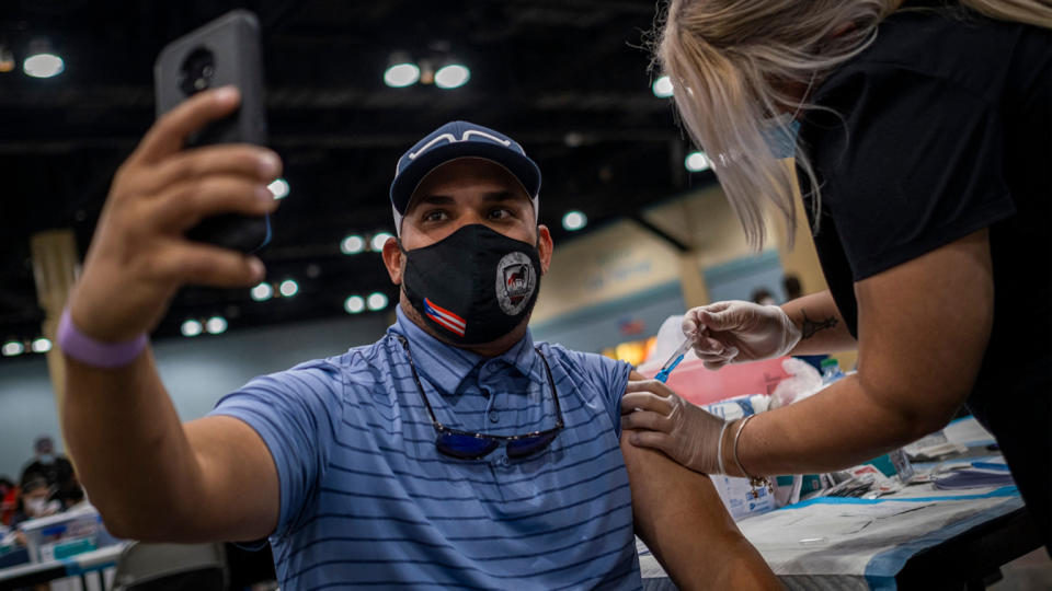 A man takes a selfie as he receives the Johnson and Johnson Covid-19 vaccine at a mass vaccination event at the Puerto Rico Convention Center in San Juan, Puerto Rico on March 31, 2021. (Ricardo Arduengo/AFP via Getty Images)