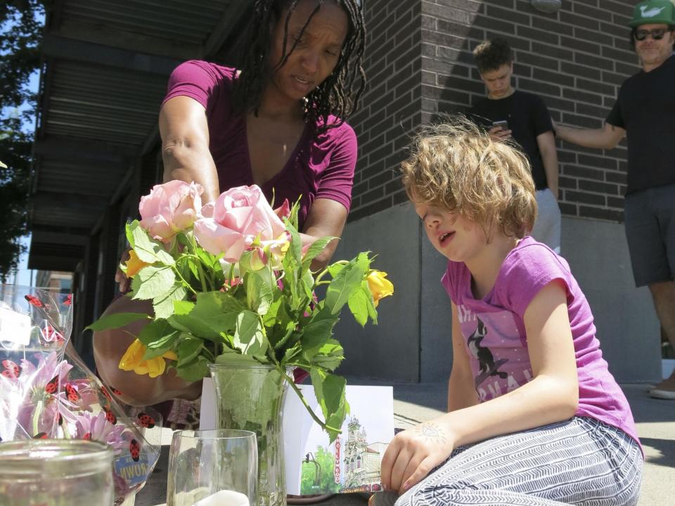 Angel Sauls, left, helps her stepdaughter Coco Douglas arrange a sign and some painted rocks she made for a memorial in Portland, Oregon, in memory of the two bystanders who were stabbed to death on Friday while trying to stop a man who was yelling anti-Muslim slurs and acting aggressively toward two young women: Gillian Flaccus/AP