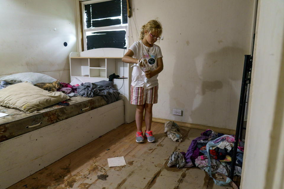 Harlee Holmes, 8, cleans out her room as her family is forced to leave their home left damaged by severe flooding in Fromberg, Mont., Friday, June 17, 2022. (AP Photo/David Goldman)