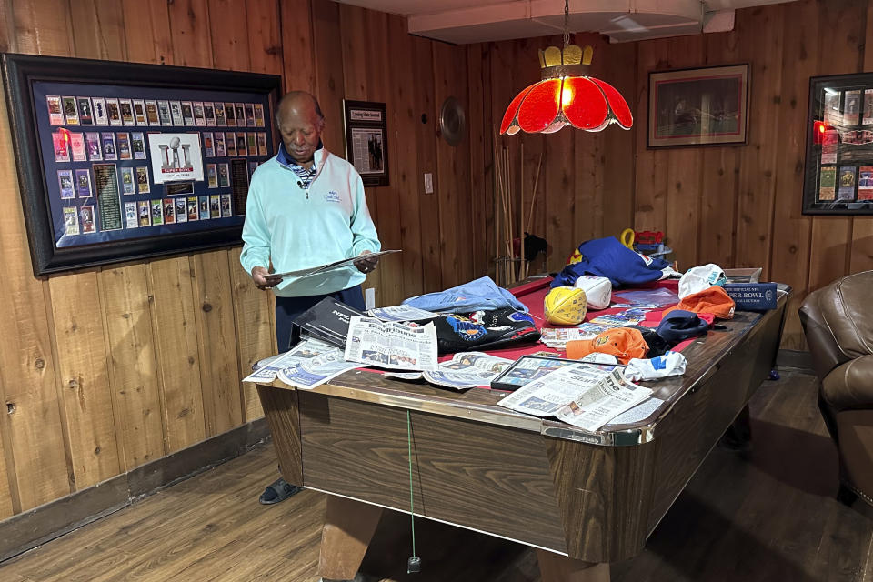 Gregory Eaton looks at some Super Bowl memorabilia at his home, Tuesday, Jan. 30, 2024 in Lansing, Mich. Eaton is a member of the exclusive "never missed a Super Bowl" club. He and two friends, all in their 80s, plan to be in Las Vegas on Sunday for Super Bowl 58. (AP Photo/Mike Householder)