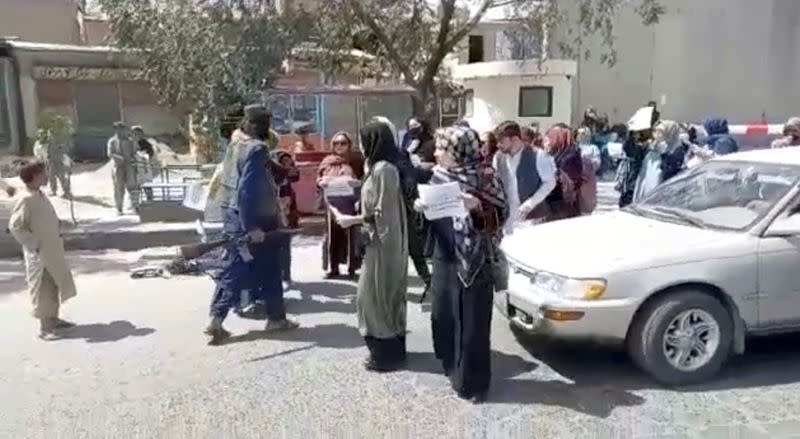 Women chant slogans as they protest next to armed men, in Kabul