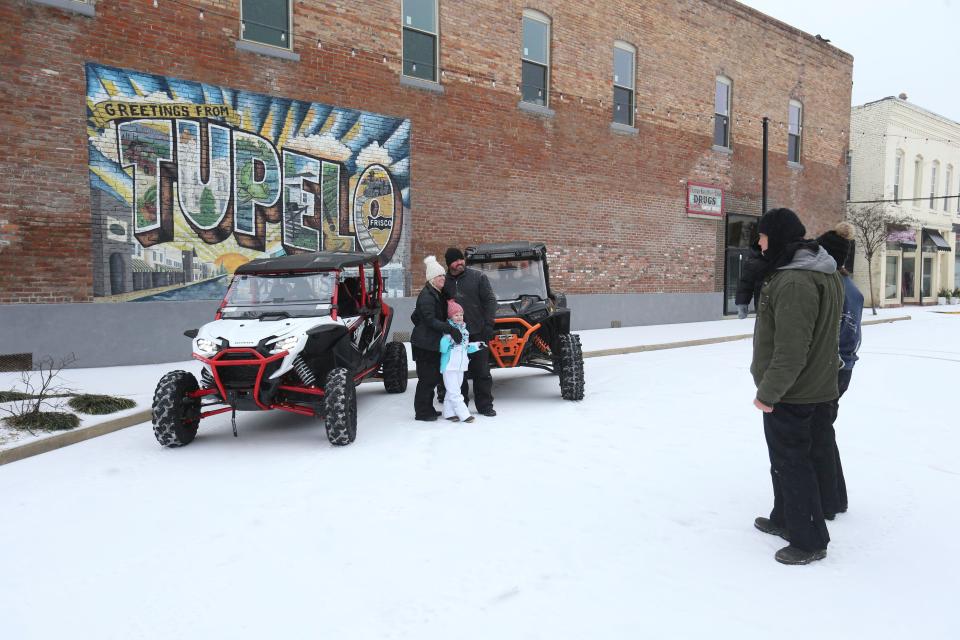 A family has a group photo taken together in the snow, Monday, Jan. 15, 2024, in downtown Tupelo, Miss., as they make their way around town in ATVs. (Thomas Wells/The Northeast Mississippi Daily Journal via AP)