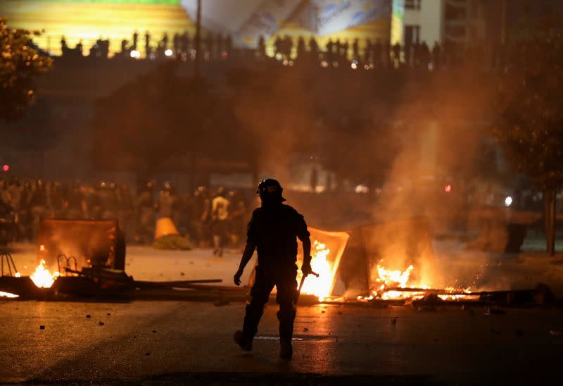 FILE PHOTO: A member of the Lebanese riot police walks near burning fire during a protest against the fall in pound currency and mounting economic hardship, in Beirut