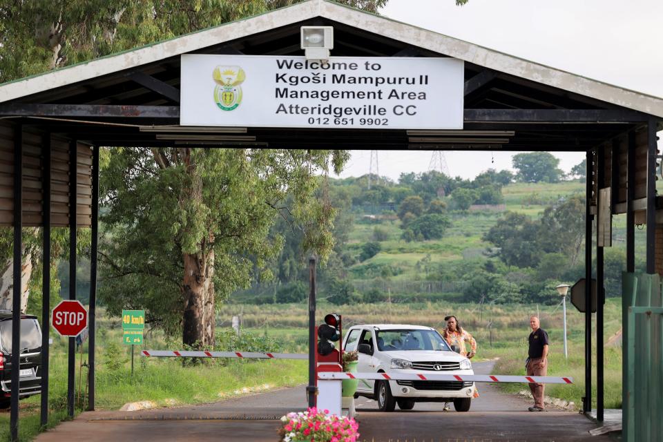 A person speaks on the phone next to a car at the entrance of the Atteridgeville Correctional Centre, where South African athlete Oscar Pistorius, convicted of killing his girlfriend Reeva Steenkamp in 2013, is due to be released on parole, in Pretoria, South Africa (Reuters)