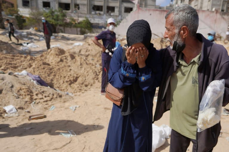 Palestinians react after the body of a relative was found buried at the Nasser hospital in southern Gaza (-)