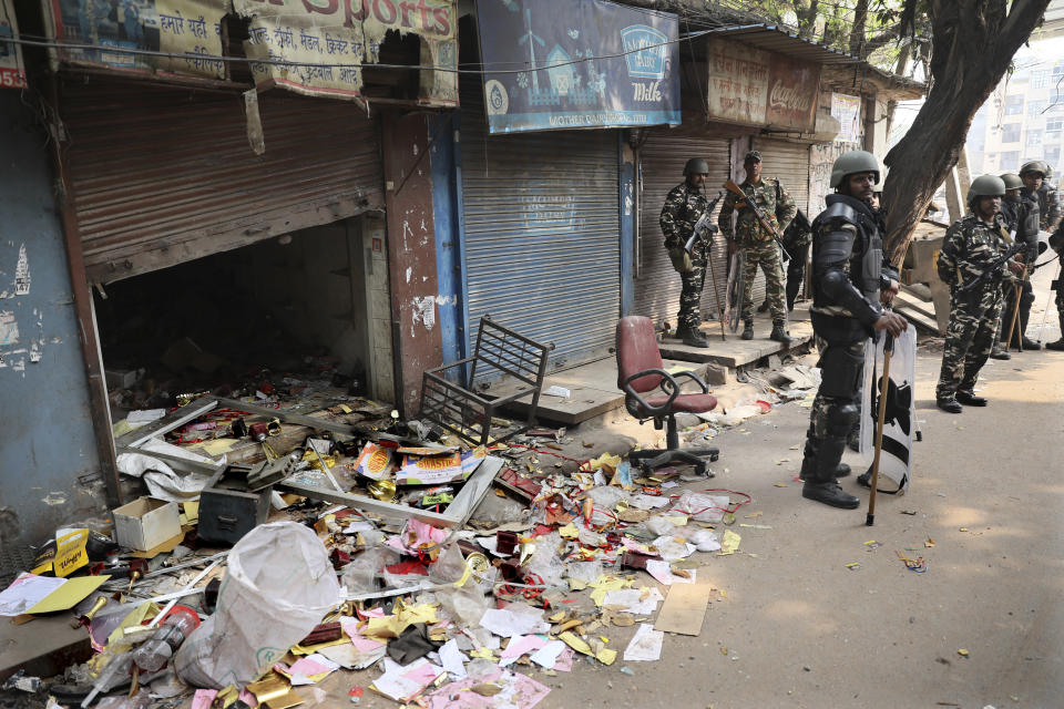 Indian paramilitary soldiers stand guard near a shop vandalised during Tuesday's violence in New Delhi, India, Wednesday, Feb. 26, 2020. At least 20 people were killed in three days of clashes in New Delhi, with the death toll expected to rise as hospitals were overflowed with dozens of injured people, authorities said Wednesday. The clashes between Hindu mobs and Muslims protesting a contentious new citizenship law that fast-tracks naturalization for foreign-born religious minorities of all major faiths in South Asia except Islam escalated Tuesday. (AP Photo/Manish Swarup)