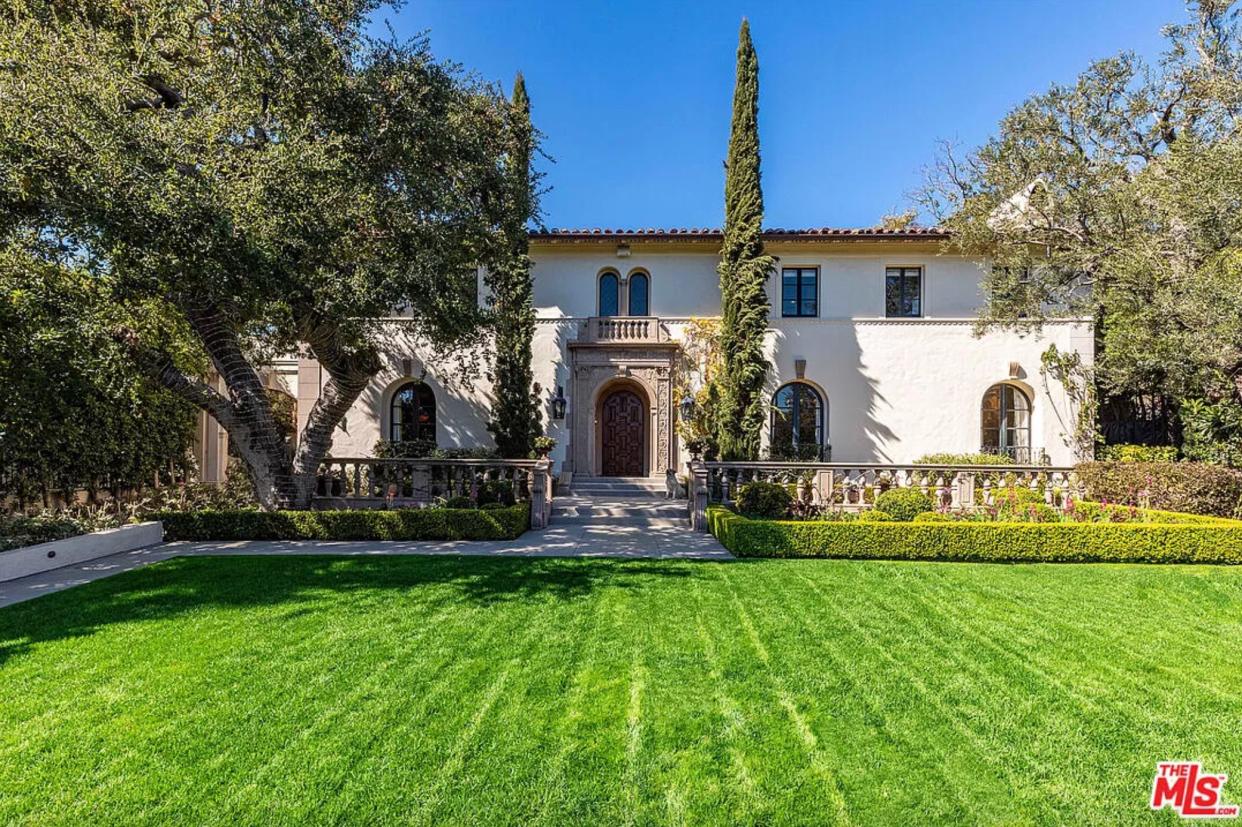 Front view of Ozzy And Sharon Osbourne mansion with bright green lawn and landscaping