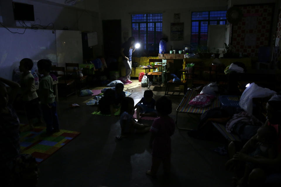 A woman uses a flashlight inside a temporary evacuation center as electricity was shut-off following the onslaught of Typhoon Mangkhut in Tuguegarao city in Cagayan province, northeastern Philippines on Saturday, Sept. 15, 2018. The typhoon slammed into the Philippines northeastern coast early Saturday, it's ferocious winds and blinding rain ripping off tin roof sheets and knocking out power, and plowed through the agricultural region at the start of the onslaught. (AP Photo/Aaron Favila)