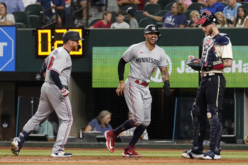 Minnesota Twins' Jordan Luplow, left, and Carlos Correa (4) celebrate at the plate after they scored on Luplow's two-run home run in front of Texas Rangers catcher Jonah Heim, right, in the seventh inning of a baseball game, Friday, Sept. 1, 2023, in Arlington, Texas. (AP Photo/Tony Gutierrez)