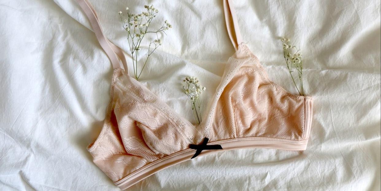 pale pink bralette and gypsophila flowers on white sheets top view