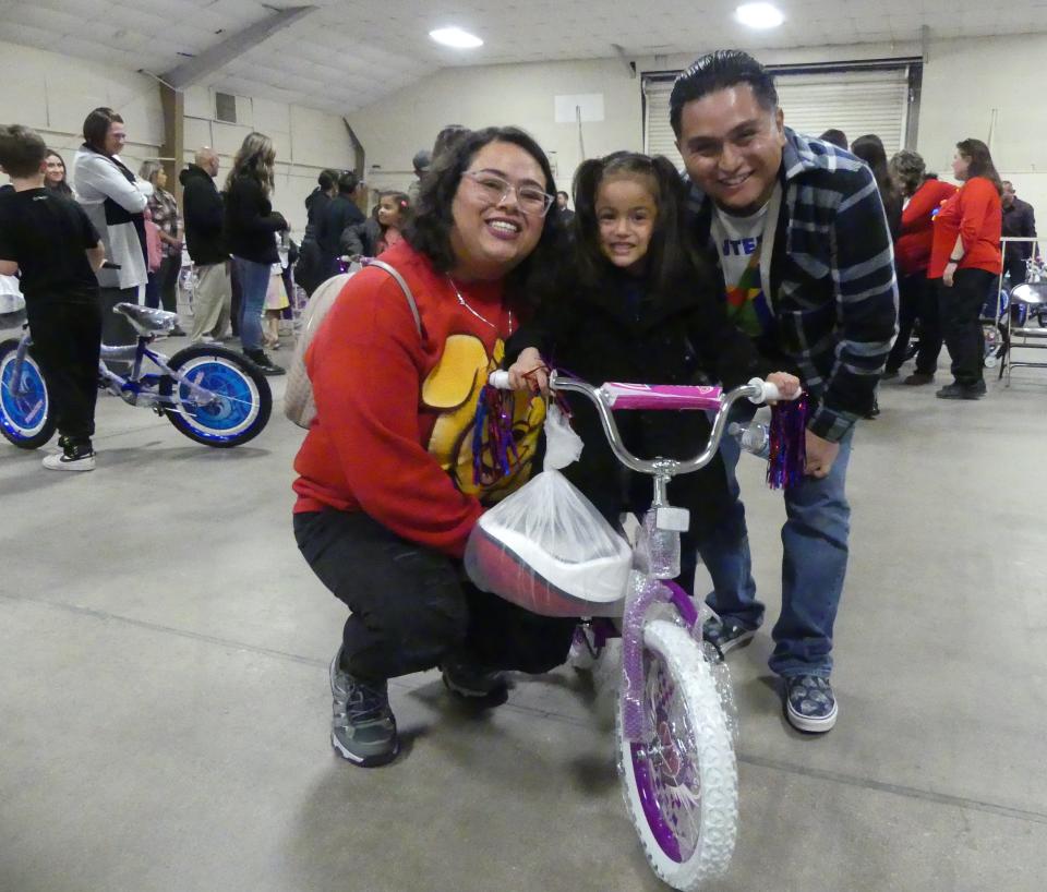 The Cortes family celebrates their daughter receiving a new bike during the 19th annual Doris Davies Memorial Bicycle Giveaway on Wednesday at the San Bernardino County Fairgrounds in Victorville.