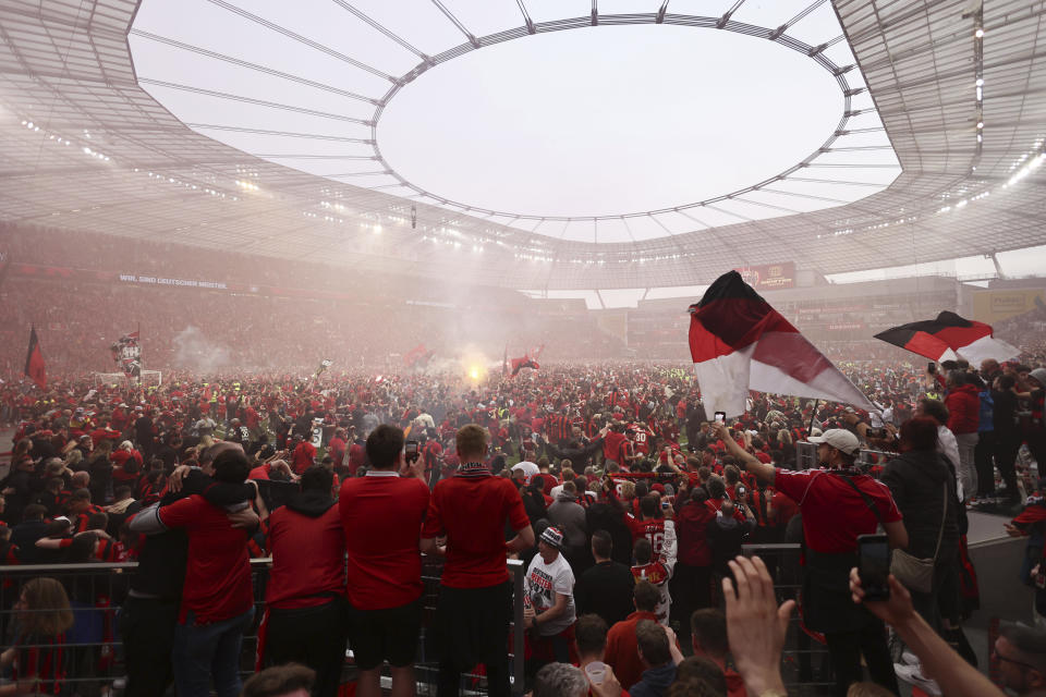 Leverkusen fans run onto the pitch to celebrate their team winning the Bundesliga after the Bundesliga soccer match between Bayer Leverkusen and Werder Bremen at the BayArena in Leverkusen, Germany, Sunday April 14, 2024. (Rolf Vennenbernd/dpa via AP)