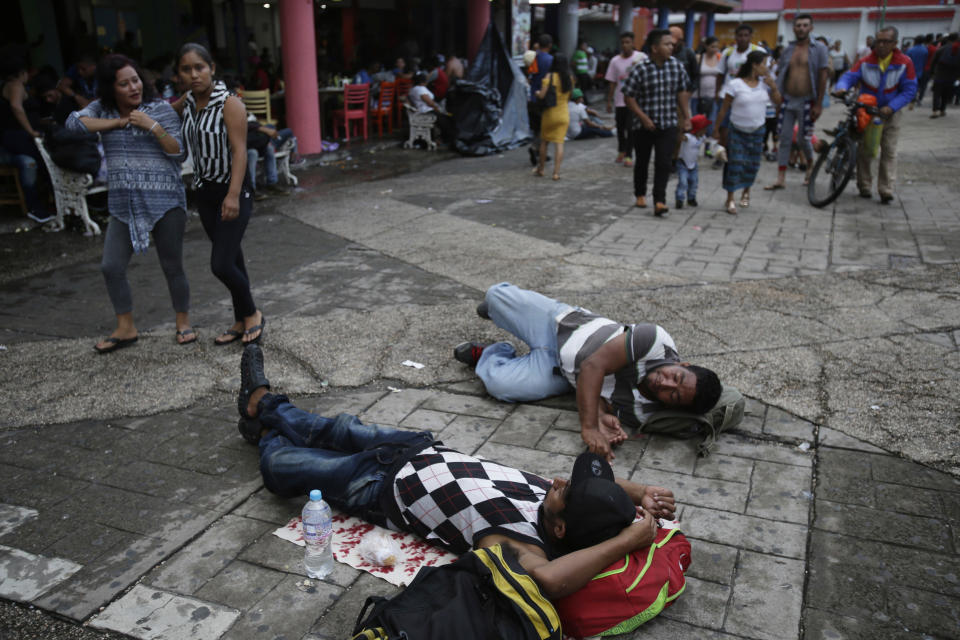 Migrantes centroamericanos que buscan llegar a Estados Unidos en una masiva caravana descansan en la acera en un parque céntrico en la ciudad de Tapachula, en el sur de México, el domingo, 21 de octubre del 2018. (AP Foto/Moises Castillo)