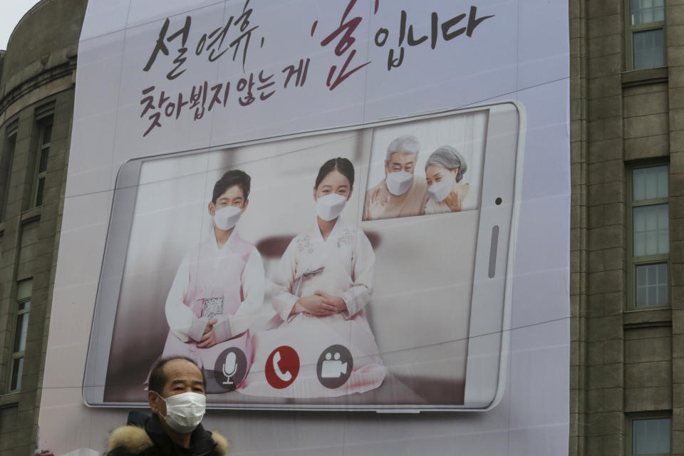 A man wearing a face mask as a precaution against the coronavirus passes by a banner calling on residents to refrain from visiting families and relatives during the upcoming Lunar New Year holidays that start Feb. 11, in front of Seoul City Hall in Seoul, South Korea, Monday, Feb. 1, 2021. South Korea on Sunday said it will maintain elevated social distancing measures for at least two more weeks as health officials raise concerns about a possible surge in coronavirus infections surrounding the Lunar New Year holidays. The banner reads: "It is a filial piety not to visit during the Lunar New Year holidays." (AP Photo/Ahn Young-joon)