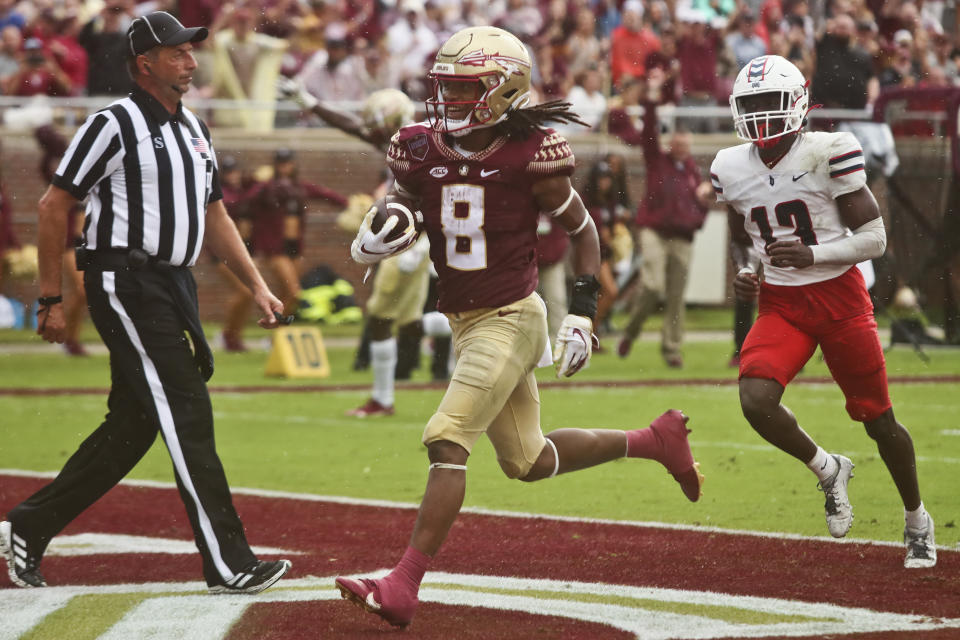 Florida State running back Treshaun Ward (8) scores a touchdown as Duquesne defensive back CJ Barnes (13) trails in the first quarter of an NCAA college football game Saturday, Aug. 27, 2022, in Tallahassee, Fla. (AP Photo/Phil Sears)