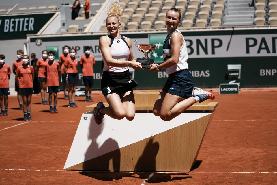 Czech Republic's Barbora Krejcikova, right, and compatriot Katerina Siniakova jump while holding the cup after defeating USA's Bethanie Mattek-Sands and Poland's Iga Swiatek in their women's doubles final match of the French Open tennis tournament at the Roland Garros stadium Sunday, June 13, 2021 in Paris. (AP Photo/Thibault Camus)