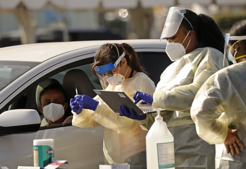 INGLEWOOD, CA - JANUARY 19: Staff and volunteers distribute the COVID-19 vaccine to people as they remain in their vehicles at The Forum in Inglewood. The Forum is one of five mass-vaccination sites that opened Tuesday in Los Angeles county. Todays inoculations were only available to front line health care workers and residents and staff of skilled nursing facilities and other long-term care facilities. Inoculations for the members of the eligible tier were administered from 10 a.m. to 4:30 p.m. Los Angeles County residents may find out when they are eligible to be vaccinated by visiting vaccinatelacounty.com, which is the county's vaccination website. The Forum on Tuesday, Jan. 19, 2021 in Inglewood, CA. (Al Seib / Los Angeles Times)