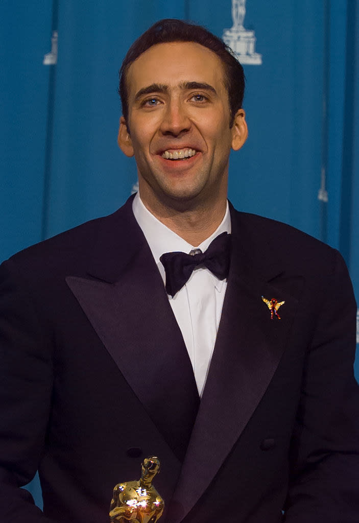 Cage smiling and holding an Oscar