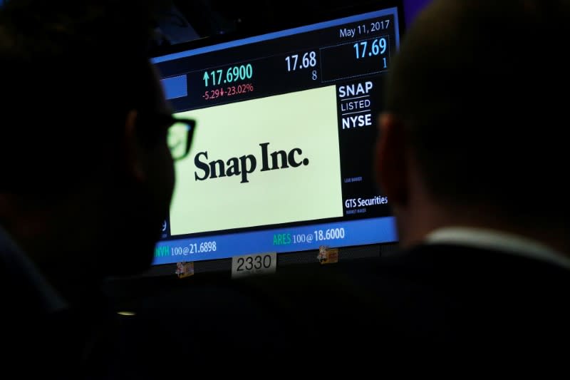 Traders look up at a screen that displays trading information for Snap Inc. on the floor of the NYSE in New York