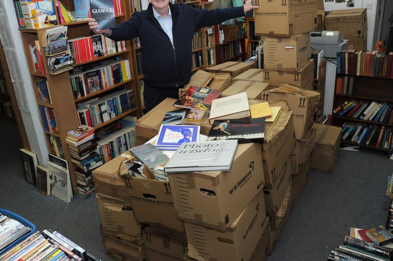 Owner Brian Hannan with over 2,000 books donated to the shop by the widow of the late author Christopher Priest