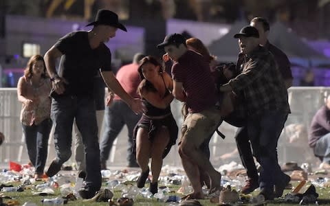 People carry a person at the Route 91 Harvest country music festival after apparent gunfire - Credit: David Becker/Getty Images