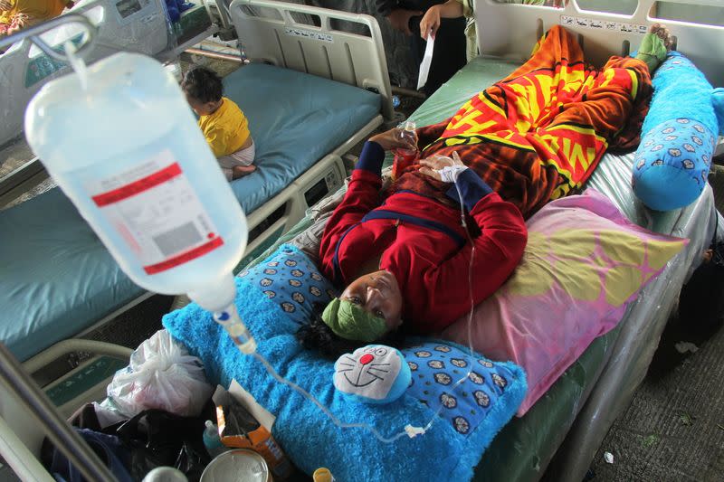 Injured woman lies at temporary shelter outside hospital following an earthquake in Mamuju