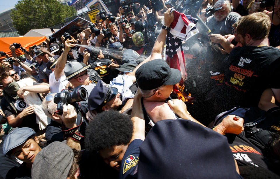 Mientras un grupo de manifestantes intentaba quemar una bandera estadounidense, la policía arrojó gas pimienta sobre las personas en una multitud cercana. Texto: AP. Foto: EFE/ David Maxwell