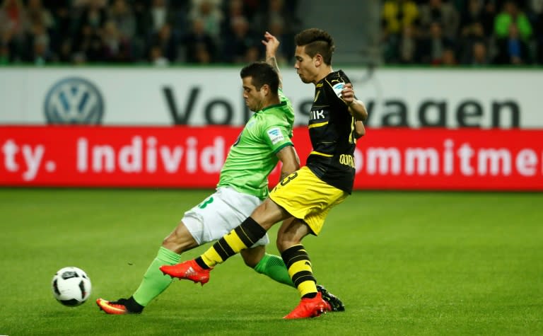 Dortmund's defender Raphael Guerreiro (R) shoots to score as Wolfsburg's midfielder Vieirinha tries to stop during the German first division Bundesliga football match between VfL Wolfsburg and Borussia Dortmund