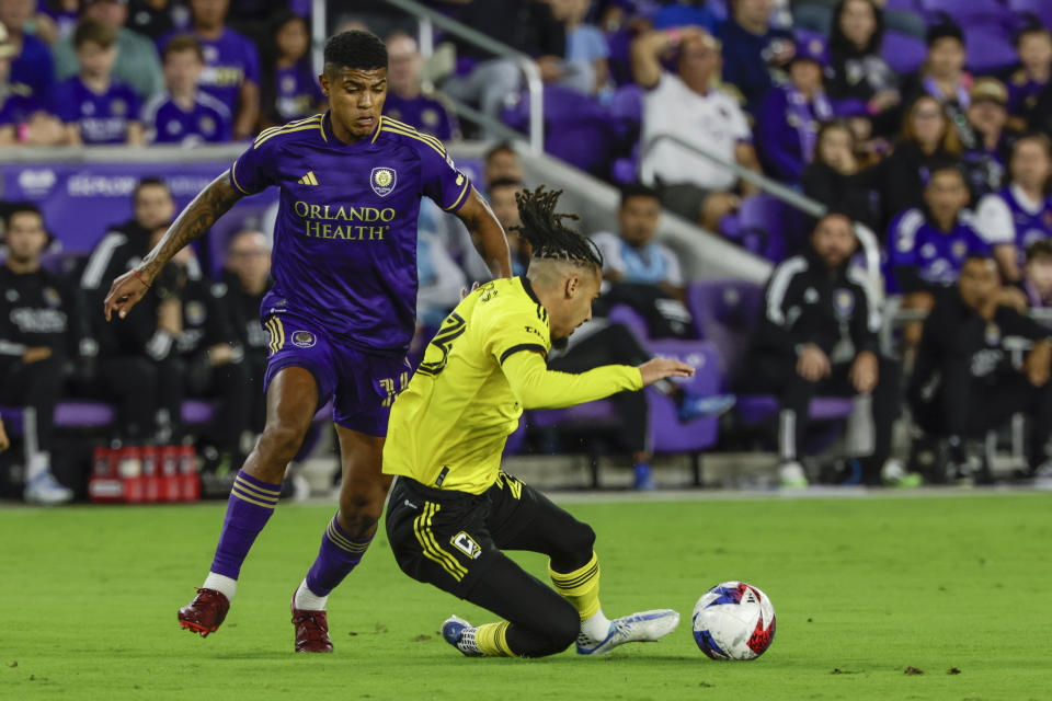 Columbus Crew defender Mohamed Farsi, right, falls being defended by Orlando City midfielder Wilder Cartagena, left, during the first half of an MLS soccer playoff match, Saturday, Nov. 25, 2023, in Orlando, Fla. (AP Photo/Kevin Kolczynski)