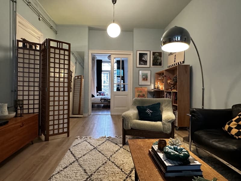 Living room with black leather vintage sofa, vintage rugs, and vintage art on the walls