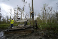 Brian Ramshur, an electrical worker for Sparks Energy, climbs a power pole to restore power lines running through a marsh, in the aftermath of Hurricane Ida in Houma, La., Friday, Sept. 17, 2021. The Louisiana terrain presents special challenges. In some areas, lines thread through thick swamps that can be accessed only by air boat or marsh buggy, which looks like a cross between a tank and a pontoon boat. Workers don waders to climb into muddy, chest-high waters home to alligators and water moccasins. (AP Photo/Gerald Herbert)