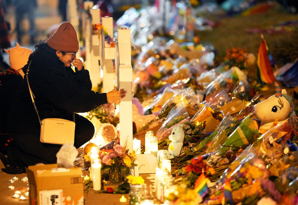 A woman cries at a cross for one of the victims of Saturday's fatal shooting at Club Q during a candlelight vigil on a corner near the site of the gay bar Monday, Nov. 21, 2022, in Colorado Springs, Colo. (AP Photo/Jack Dempsey)