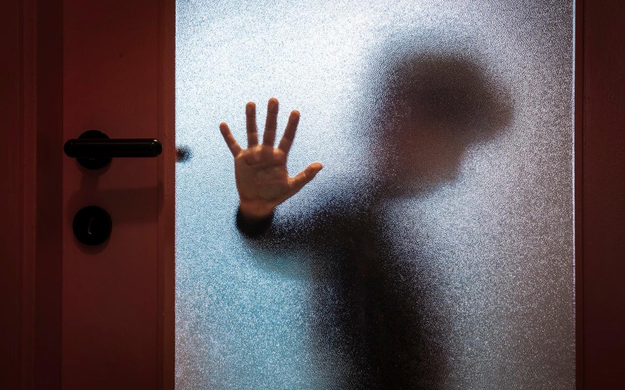 Blurred sad boy leaning open hand against glass door